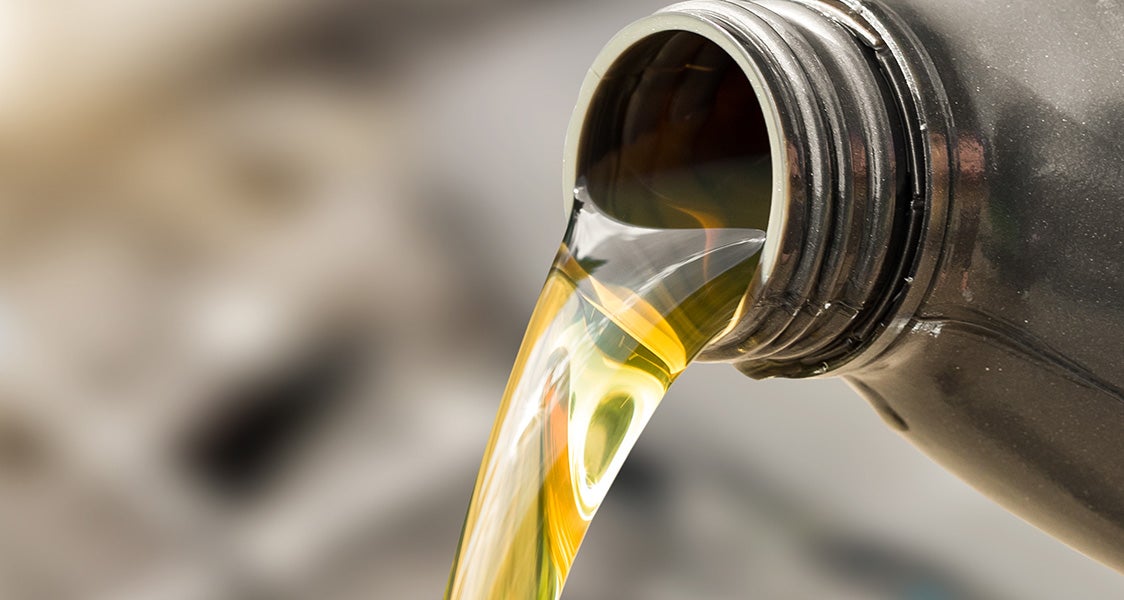 Close-up of motor oil being poured from a container for vehicle maintenance.